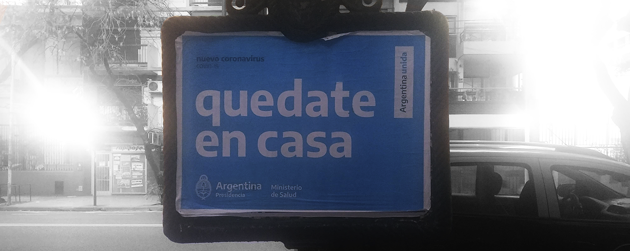 A imagem mostra uma placa, na cidade de Buenos Aires, com a escrita 'quedate en casa'