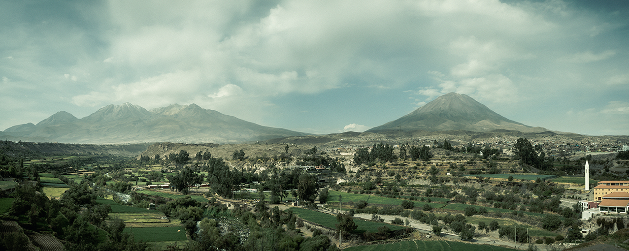 A imagem mostra o vulcão Misti, no Peru, ao fundo com árvores e casas na frente.